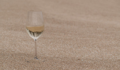 a glass of wine on a deserted shore in the sand