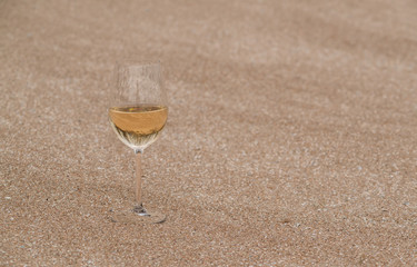 a glass of wine on a deserted shore in the sand