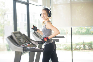 Fototapeta premium Pretty young sport woman is running on treadmill in gym, Healthy lifestyle