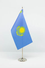 State desktop flag of Kazakhstan on metal flagpole isolated on white background. National symbol