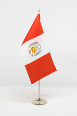 State desktop flag of Peru on metal flagpole isolated on white background. National symbol