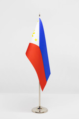 State desktop flag of Philippines on metal flagpole isolated on white background. National symbol
