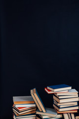 many stacks of educational books in the university library on a black background