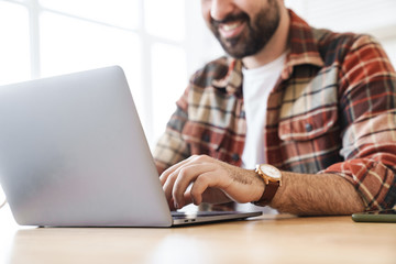 Cropped portrait of cheerful man working with laptop and smiling