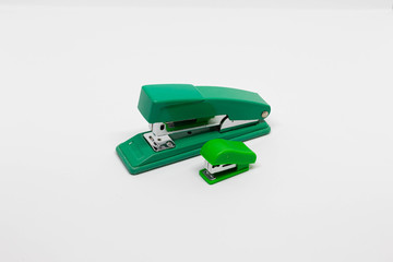 Two green plastic and metal staplers, small and medium size, isolated on white background. Closeup....