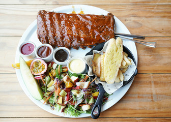 Delicious barbecued ribs seasoned with a sauce. BBQ Ribs served with fresh vegetables on white...