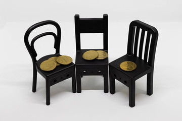 Coins on mini toy chairs isolated on white background. Chair design, modern style