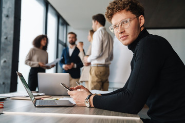 Fototapeta premium Attractive young confident businessman sitting at the office