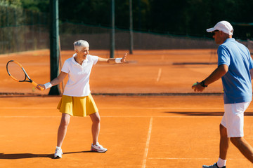 Older Woman Practicing Tennis with Instructor