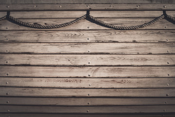 The side of an old wooden boat with ship rope. Marine wood texture background with copy space.