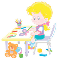 Smiling little girl sitting at her table among toys and drawing with color pencils a funny picture of a small beautiful butterfly, vector cartoon illustration on a white background
