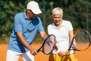 Tennis Instructor with Senior Woman on Clay Court. Woman having a Tennis Lesson.