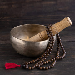 Mala beads and tibetan singing bowl on wooden square background.  Mindfulness or meditation concept.