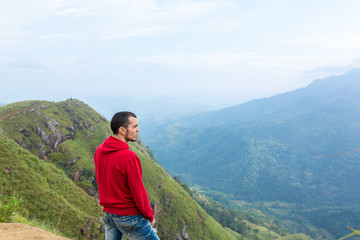 Naklejka premium A man enjoying the mountain scenery on the edge of a cliff