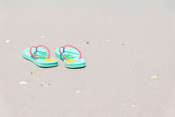 Green flip-flops on the sand at the sea with copy space , summer holiday and vacation concept.Selective focus