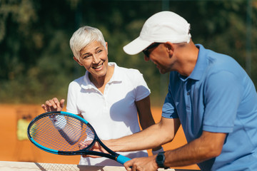 Fototapeta premium Tennis Coach Practicing Service with Senior Woman on Outdoor Tennis Class.