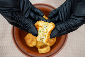 fried potato cutlets in a bowl and in the hands of a person