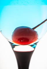 Blue martini cocktail with cherry on the white background. Selective focus. Shallow depth of field.