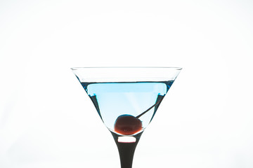 Blue martini cocktail with cherry on the white background. Selective focus. Shallow depth of field.