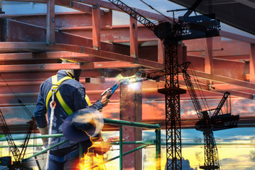 Double exposure of electric welder works on scaffolding, Safety,Construction wearing safety harness...