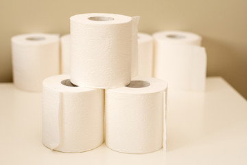 Toilet paper rolls pile on neutral background. Shortage and stockpile concept