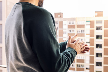 man clapping from his balcony during the pandemic