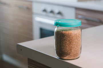 Glass jar of wheat groats on the table in kitchen