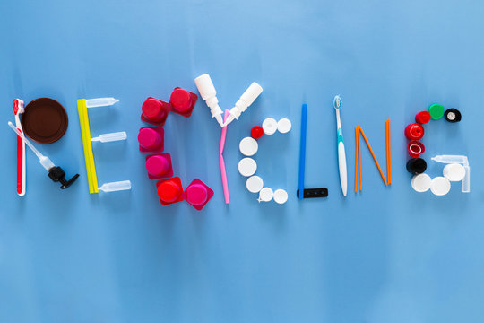 The word recycling composed with various plastic garbage items on colorful background