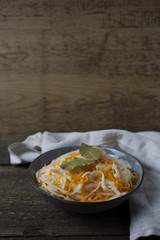 fermented white cabbage on a gray plate on a wooden background