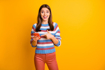 Portrait of her she nice attractive lovely cheerful cheery glad brown-haired girl holding in hands cell showing online shop app 5g isolated on bright vivid shine vibrant yellow color background