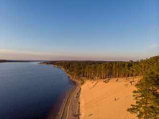 Beautiful drone areal photography view of large dune and pine forest near river Lielupe. Photo taken on sunset.