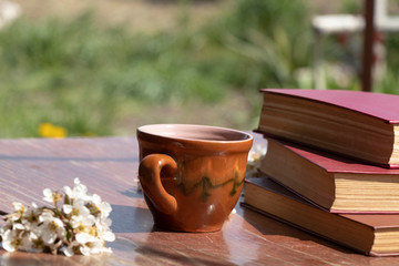 Spring flowering in a mug on a wooden background. Beautiful floral background. Reading books freshly with a cup of coffee. Spring.