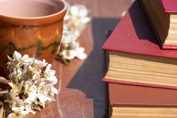 Spring flowering in a mug on a wooden background. Beautiful floral background. Reading books freshly with a cup of coffee. Spring.