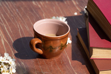 Spring flowering in a mug on a wooden background. Beautiful floral background. Reading books freshly with a cup of coffee. Spring.
