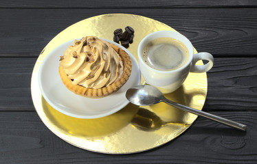 A basket of cream cake and a cup of coffee on the table. Confectionery in the coffee shop. A cup of hot coffee in a white cup.
