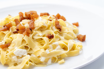 close up of fresh homemade pasta with cheese and fried bacon