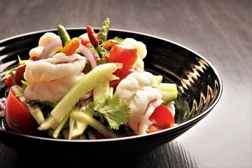 Spicy shrimp salad bowl with tomato. cucumber,red onion,cilantro or coriander, fresh chili.photo isolate on black copy space front view