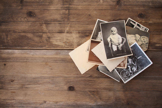 old vintage monochrome photographs in sepia color are scattered on a wooden table, the concept of genealogy, the memory of ancestors, family ties, memories of childhood