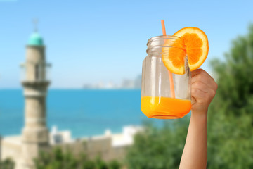 cheerful kid holds a glass jar in his outstretched hand with orange juice from an orange or lemon with a straw, the concept of a healthy diet, vitamins, lifestyle