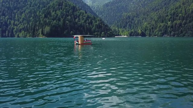 Lake Ritsa Abkhazia shooting over the water. 25.07.2018. the boat with the tourists.