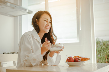 Young woman asia wake up refreshed in the morning and relaxing eat coffee, cornflakes, bread and...