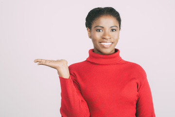 Cheerful African American lady holding copy space. Smiling young woman showing empty palm. Advertising concept