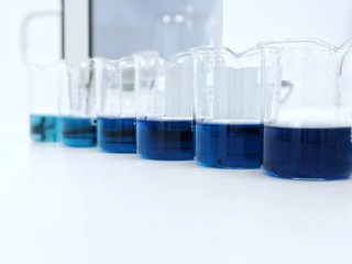 The beakers with blue color range  solution on bench laboratory, with stannous chloride solvent for analysis phosphate experiment in waste water sample. bright light effect using for clean room.