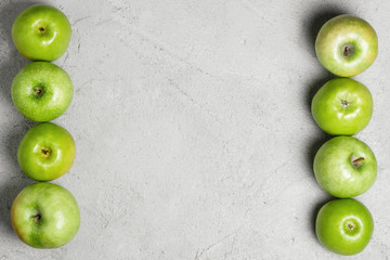 Green apples on a gray concrete background. Harvest apples, summer season, fresh fruits. Top view, flat lay, copy space.