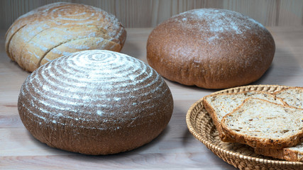 sliced ​​bread slices in a straw basket and round loaves of wheat bread on the kitchen table. Healthy eating concept