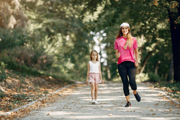 Fototapeta premium Beautiful mother with little daughter. Girls doing sport. Family in a sportswear.