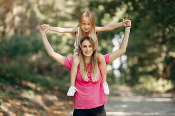 Obraz premium Family in a summer park. Mother in a pink t-shirt. Cute little girl