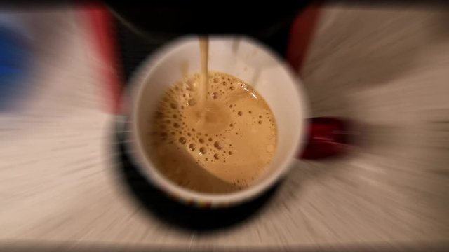 slow motion video of coffee that flows slowly into the cup making sketches. Video with concentric tilt-shift effect