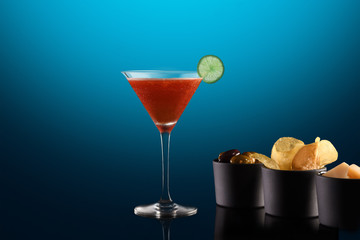 Beautiful cocktail isolated on blue background with dry ice smoke.