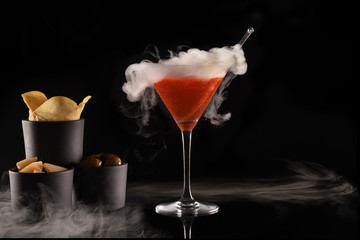 Beautiful cocktail isolated on black background with dry ice smoke.